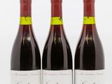 three bottles of red wine sitting on top of a white table