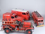 trois camions de pompiers miniatures et un camion de pompiers posés sur une surface blanche