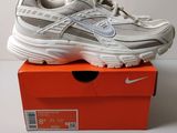 une paire de baskets blanches posée sur une boîte rouge
