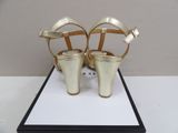 pair of women ' s gold high heeled sandals on display in a black box