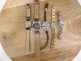 a lot of watches and bracelets sitting on a table