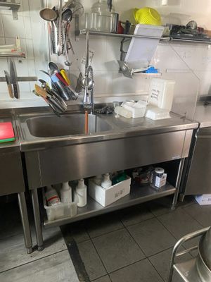 un grand évier en inox dans une cuisine remplie d'ustensiles