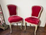 pair of red velvet chairs in a white room with a wooden floor