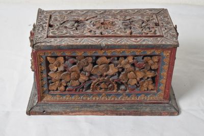 une vieille boîte en bois sculptée posée sur une surface blanche