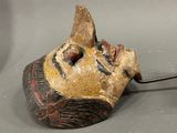a wooden mask with a metal hook attached to it