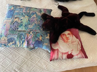 a black cat laying on a bed next to a pillow with a picture of a nun on it
