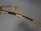 a gold plated sword with a black handle on a gray background