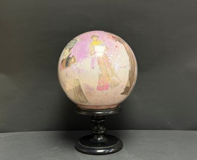 une boule en marbre rose et doré posée sur un socle noir