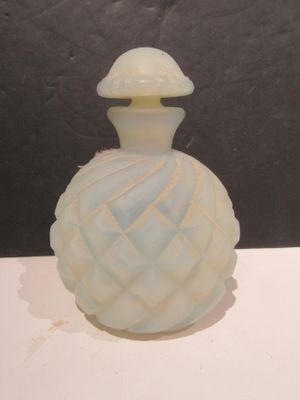 une petite bouteille en verre avec un bouchon blanc posée sur une table