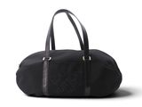 Le grand sac de voyage noir est posé sur une surface blanche.