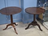 une paire de tables d'appoint anciennes sur pied, placées devant une vitrine en verre