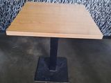 une table en bois avec un piètement en métal noir et un mur orné de motifs en arrière-plan