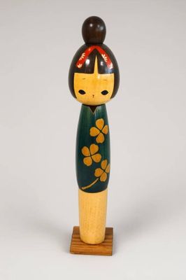 poupée en bois avec une robe verte et un nœud rouge