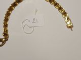 a close up of a gold chain bracelet on a white surface