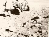 photographie en noir et blanc d'un homme sur la Lune avec un chariot rempli d'objets