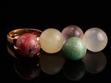 un gros plan sur trois bagues ornées de pierres de différentes couleurs, posées sur une surface noire