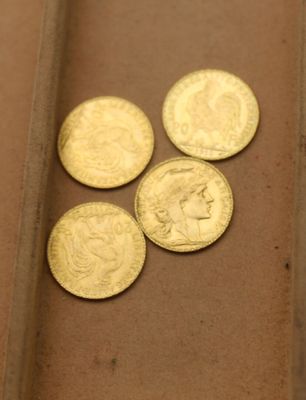 quatre pièces d'or posées sur une table, à côté d'une règle