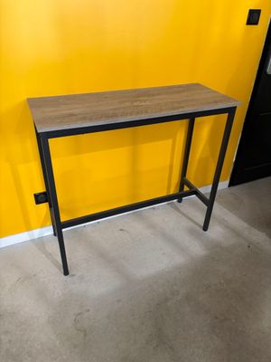 une table en bois avec des pieds en métal, adossée à un mur jaune