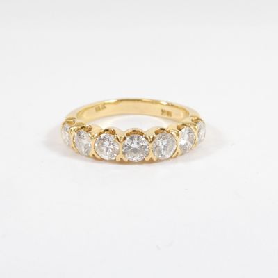 a yellow gold ring with five round diamonds on a white background