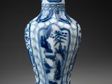 blue and white vase with figures on it on a gray surface