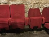 four red chairs are lined up against a stone wall