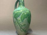 a green vase that has a vine design on it