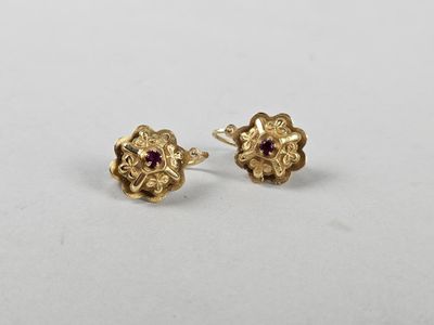 a pair of gold earrings with a ruby stone in the center