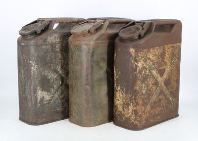 three old rusty metal cans are lined up against a white background