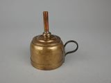 an old brass teapot with a wooden handle on a white surface