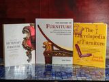 Trois livres sont posés sur une table, devant laquelle se trouve une chaise.