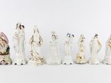 seven figurines of women dressed in white and gold
