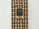 une montre noire et dorée montée sur un bracelet à maillons dorés