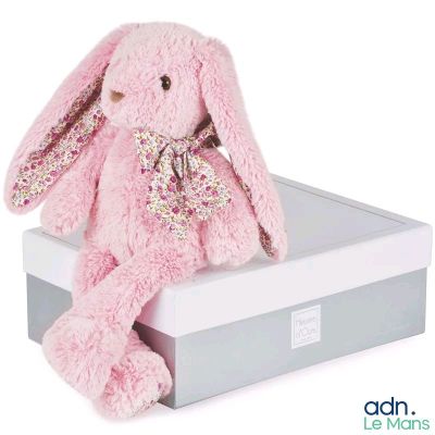 lapin en peluche rose posé dans une boîte-cadeau sur fond blanc