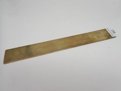 une plaque en laiton posée sur une surface blanche, avec une étiquette