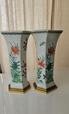 two vases sitting on a table with a curtain in the background