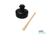 a small black bottle with a wooden stick next to it