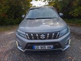 the front end of a silver suzuki suv parked on a gravel road