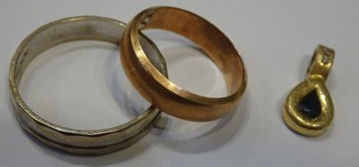two rings and a gold pendant on a white surface