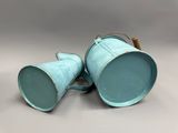 une paire de seaux métalliques bleus posés sur une table blanche