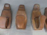 three pairs of leather holsters are lined up on a table