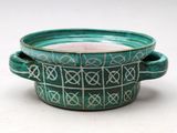 a green bowl with a handle on a white surface