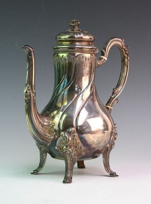 a silver tea pot sitting on a stand on a table