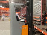 a fork lift truck in a warehouse with a pallet in the foreground