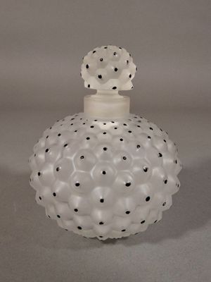 une image représentant un flacon de parfum en verre blanc parsemé de points noirs