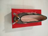 Quelqu'un tient une paire de chaussures posée sur une boîte rouge.