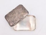 a small silver box with a flower design on it