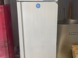 un réfrigérateur blanc sur lequel est collé un autocollant bleu, dans une pièce