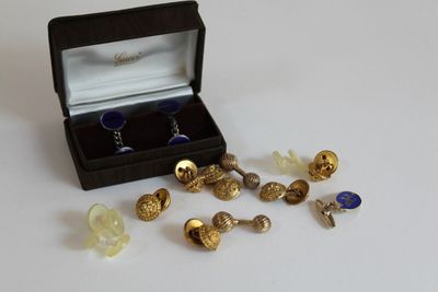 une boîte de boutons de manchette et une paire de boutons de manchette posés sur une table