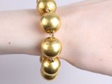 bracelet made of gold balls on a woman ' s arm
