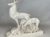une statue blanche représentant un cerf et un faon posés sur un rocher